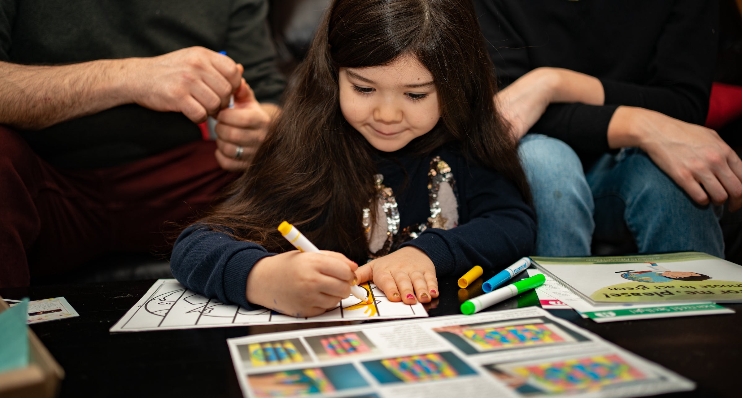 a young girl with her parents works on a project about environmental sustainability 